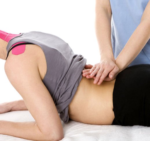 A physiotherapist applying manual therapy to a patient's lower back during a treatment session