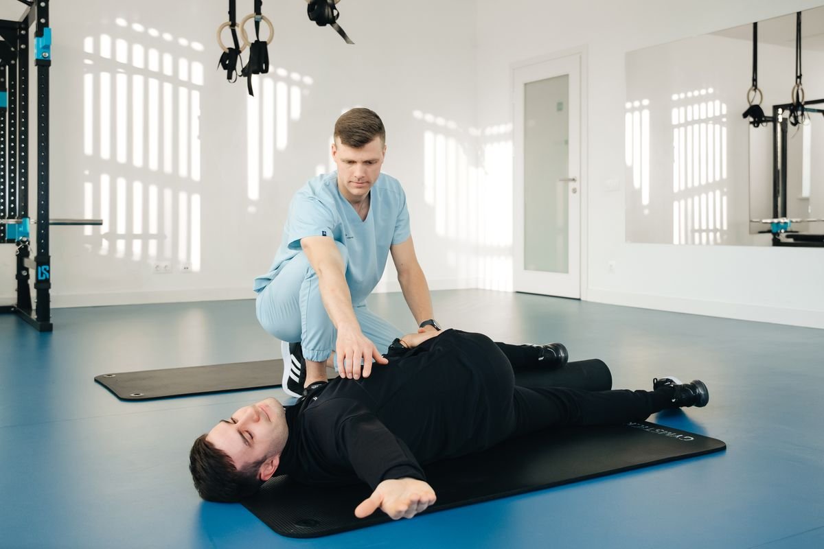 A physiotherapist working with a patient lying on a mat during post-operative rehabilitation